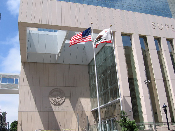 Flags in a pleasant breeze. The new courthouse, most expensive in California, has faced various construction delays.
