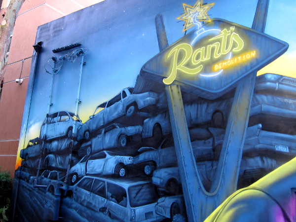 Lots of old wrecked cars are piled up behind Rant's Demolition neon sign!