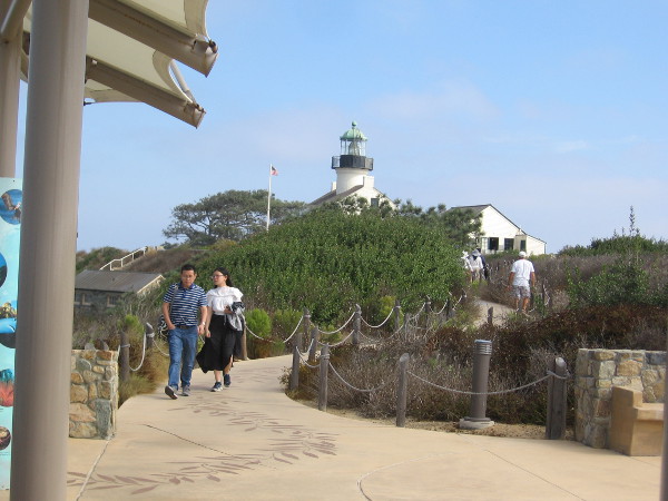 South of the lighthouse, people walk toward the gray whale migration overlook.