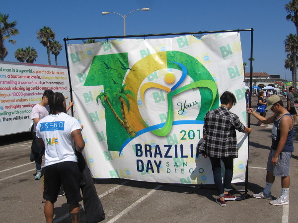People hang a banner as the San Diego Brazilian Day Festival gets started late in the morning.