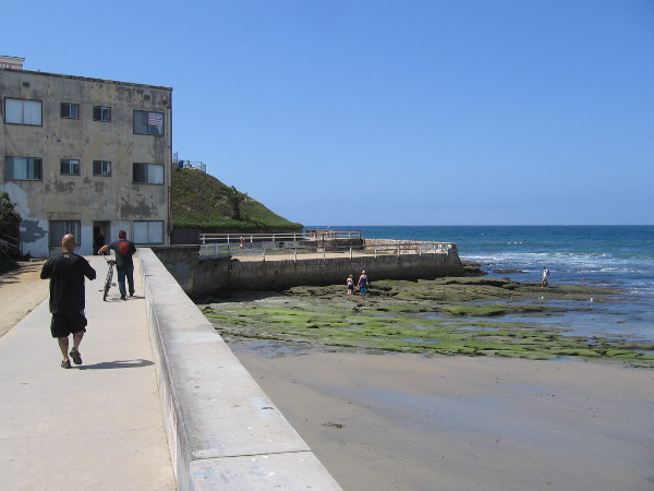 Walking south along the Ocean Beach boardwalk near the foot of the OB Pier, toward the old Silver Spray Apartments and Plunge.