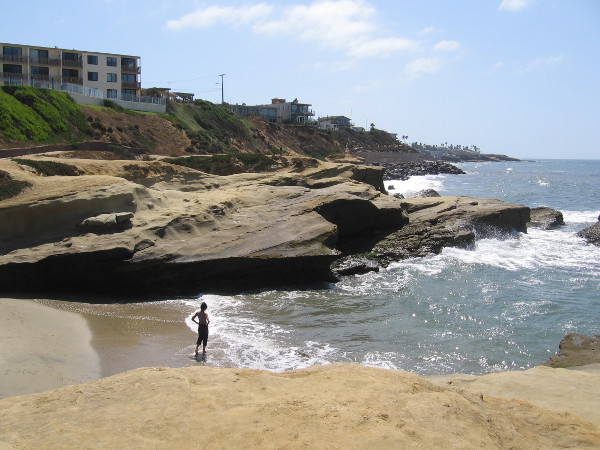 Standing on a tiny beach at the water's edge.