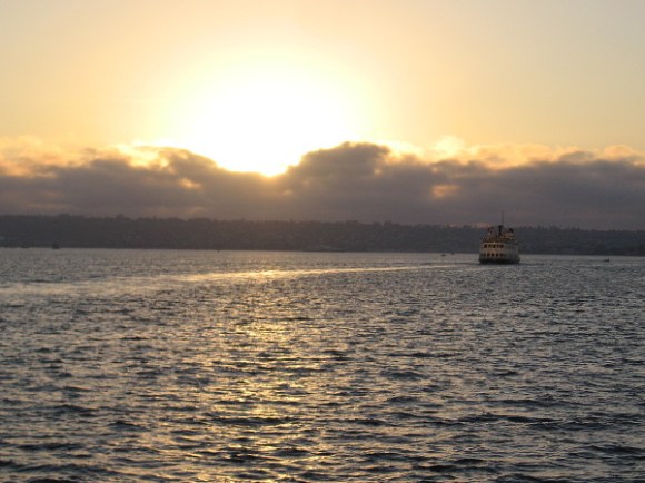 A trail of gold gleams behind a ship heading into evening darkness.