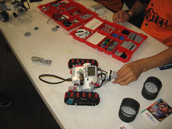 A student participating in the First Robotics Competition demonstrates a small vehicle that they built. Many robots can be seen up close in the San Diego History Center.