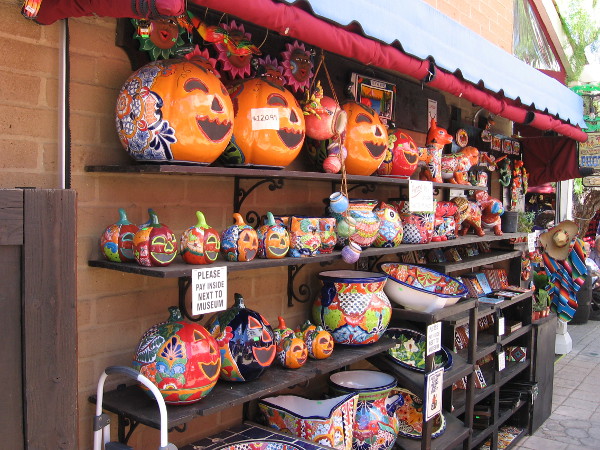 Ceramic pumpkins line shelves at an outdoor Old Town marketplace.