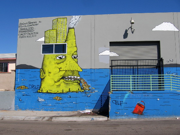 The left side of the mural shows an ugly yellow head spewing pollution into the water.
