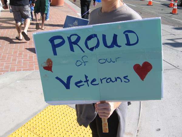 Someone hold a sign that reads Proud Of Our Veterans.