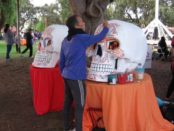 An artist paints two large skulls--calaveras--in Old Town's Plaza de las Armas during Dia de los Muertos.