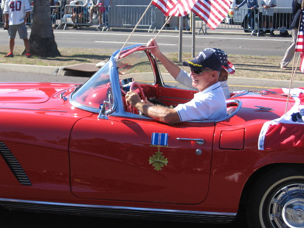 Member of the Distinguished Flying Cross Society passes in a classic car.