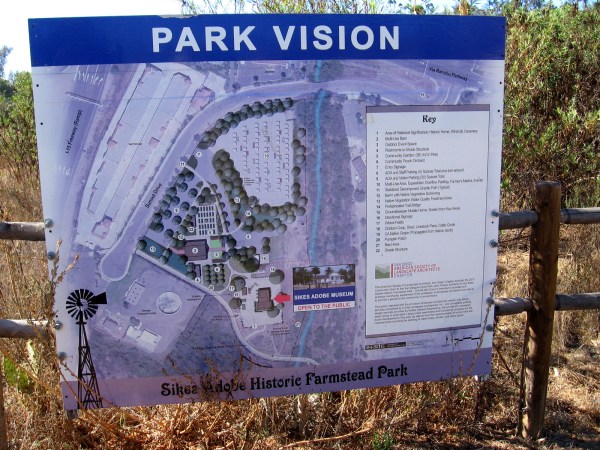 A sign shows proposed improvements to the Sikes Adobe Historic Farmstead Park, including event space and a reconstructed barn.