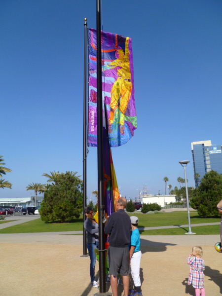 Rehearsal of a flag raising. The public art unveiling ceremony takes place later this week. That unfurled banner shows Ted Williams fielding a ball. Photo courtesy Bill Swank.