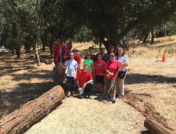 Maxwell Thomson poses with friends among logs which now mark the trail through the revitalized USS Bennington Memorial Oak Grove!