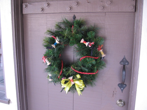 This holiday wreath is decorated with spools of thread! It hangs on a door at Threads of the Past.