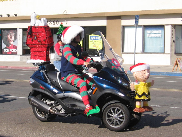 Here comes Charlie Brown, Snoopy and Woodstock on an elf-driven motorcycle!