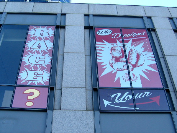 Thought-provoking graphics in the windows of MCASD's downtown gallery at America Plaza.