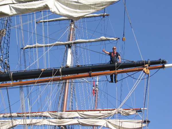 A wave from a crew member working high up on a yard of the beautiful three-masted clipper ship Stad Amsterdam.