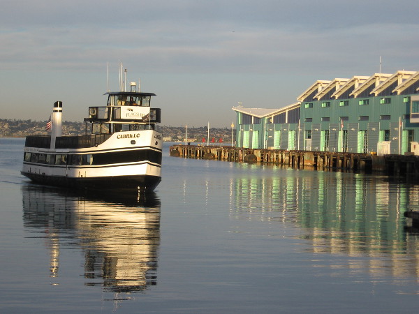 Flagship's ferry ship Cabrillo arrives at the Embarcadero. Emerald light on the bay is reflected from the Port Pavilion on Broadway Pier.