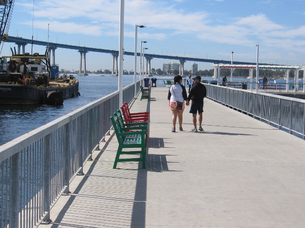 A couple walks toward the end of the Cesar Chavez Park public pier.