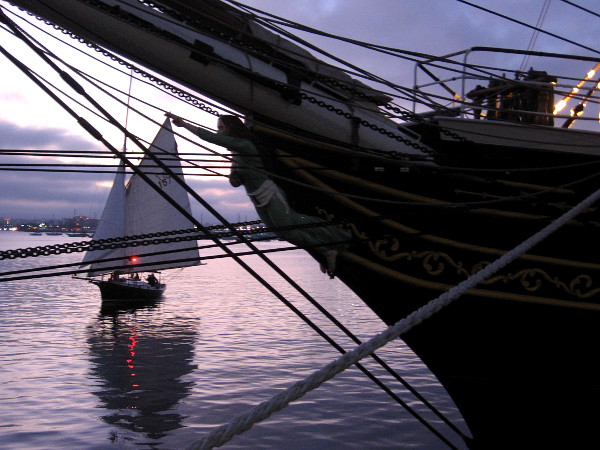 A sailboat cruises on gleaming San Diego Bay past the figurehead of Stad Amsterdam.