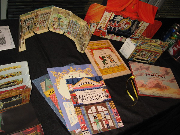 Objects on display include books, posters and materials to craft paper theaters.