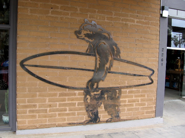 Art on wall of Everyday California Adventures and Apparel shows a bear carrying a surfboard.