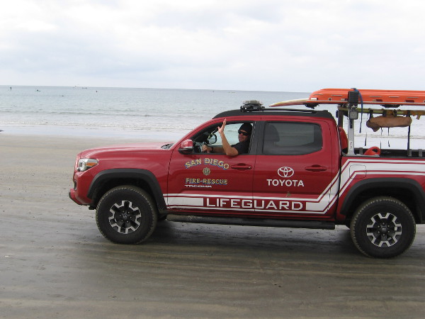 A friendly San Diego lifeguard driving past waves hello!