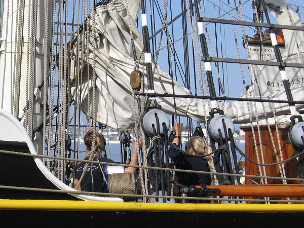 Members of the Stad Amsterdam crew work together to manipulate a sail.