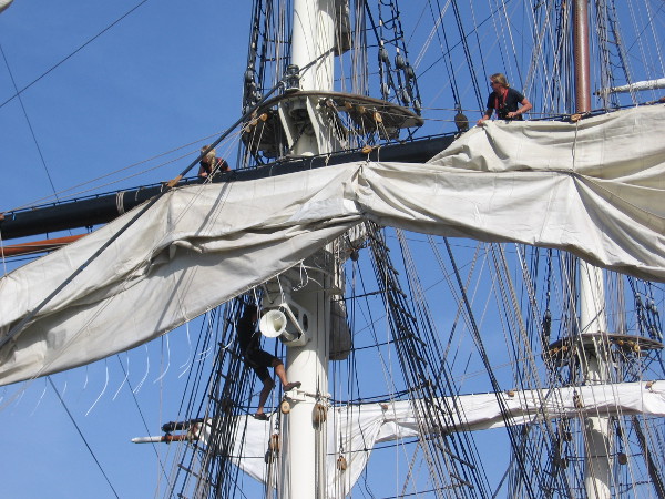 Crew members wrestle with a sail.