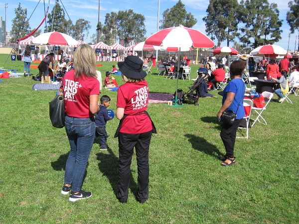 Friendly people from the Port of San Diego's Public Art Program look on as the crowd slowly grows at Cesar Chavez Park.