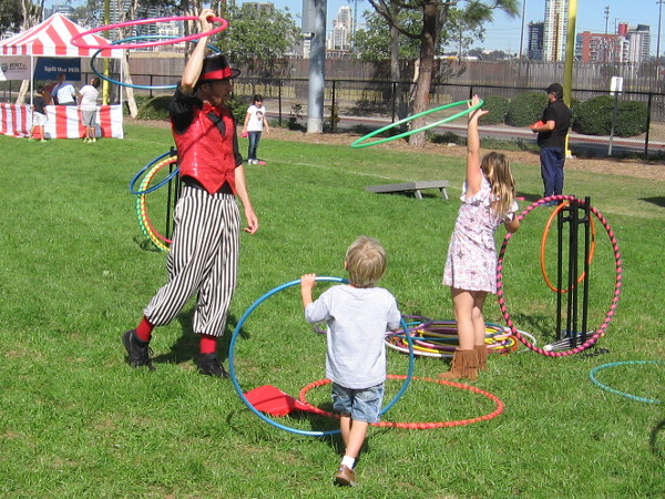 The circus juggler and some kids play with colorful hula hoops.