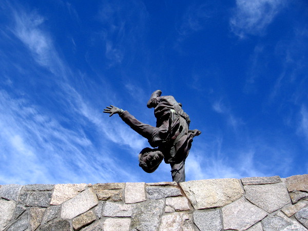 A daring man does a one-armed handstand at the edge of a high roof!