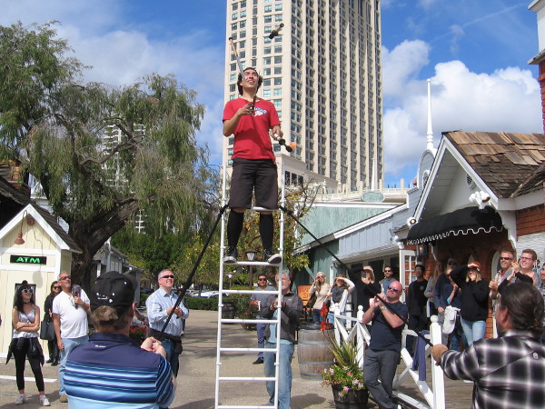 Sam Malcolm, a juggling comedian from Denver, Colorado, performs high atop a ladder during the Seaport Village Spring Busker Festival!