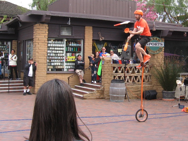 More juggling. This time atop a super tall unicycle.