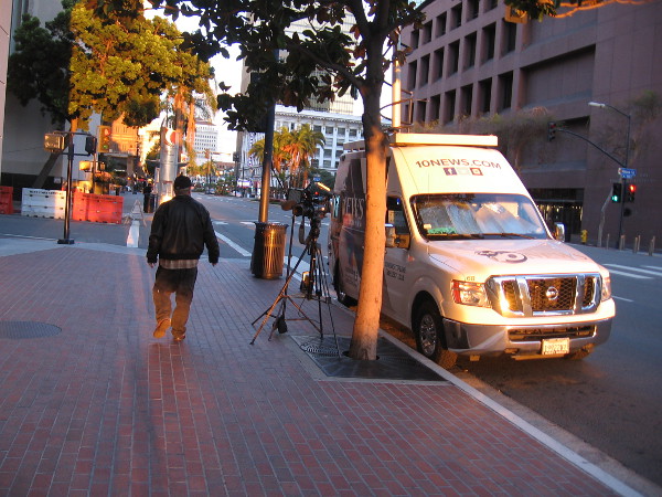 A TV news van is parked by the Hall of Justice one evening.