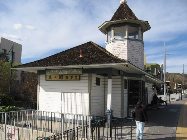 People wait for an Orange Line trolley at the Lemon Grove station. The original structure had an open cupola so the depot agent could wave signal flags at oncoming trains.
