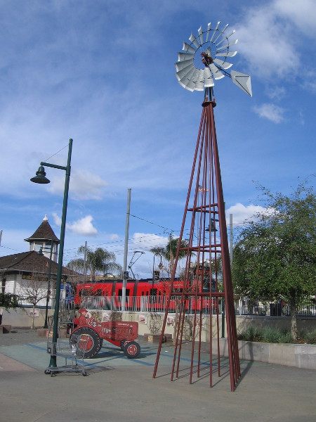 A farm's windmill and tractor are reminders of an agricultural past. They stand in a public park beside the Lemon Grove Trolley Depot.