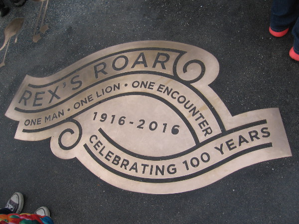 Inlaid near the public art's base is the shiny inscription Rex's Roar. One Man - One Lion - One Encounter. 1916-2016. Celebrating 100 Years.