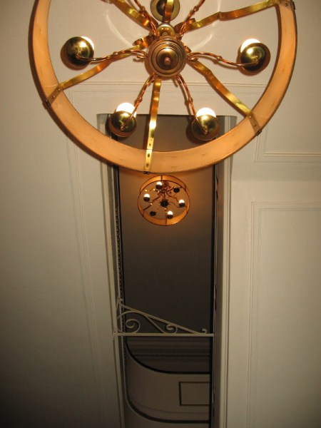 Looking up at light fixtures, one at the theatre lobby and one up some stairs at the Mezzanine.