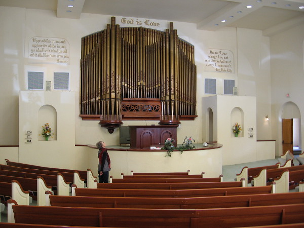 Like a crown of gold, organ pipes dominate the altar of a light-filled sanctuary.