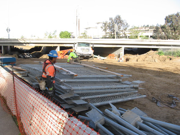 Construction worker by stacked fencing.