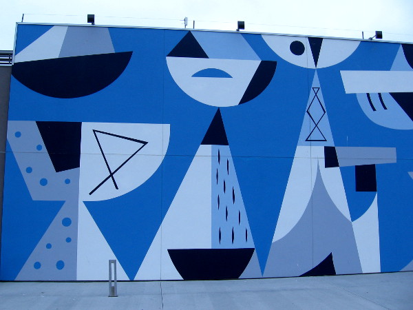 Left half of mural by Rafael Lopez outside Coasterra on Harbor Island seems to depict abstract boats and the San Diego skyline across the bay.