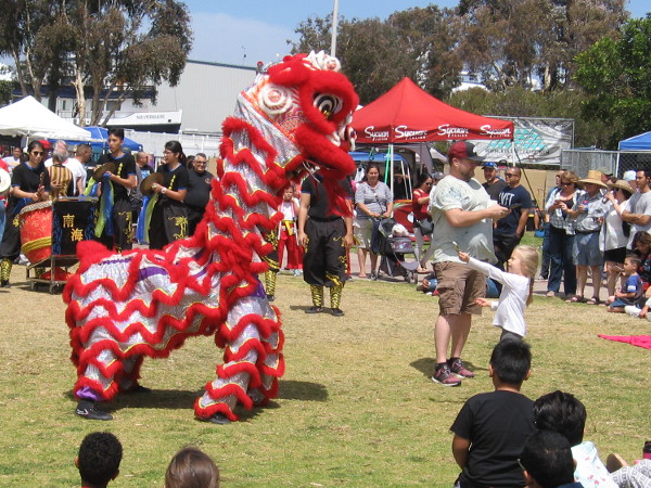 A young girl offers the red lion a dollar bill for good luck.