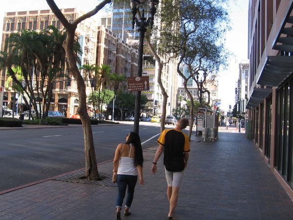 A couple walks along Broadway in downtown San Diego.