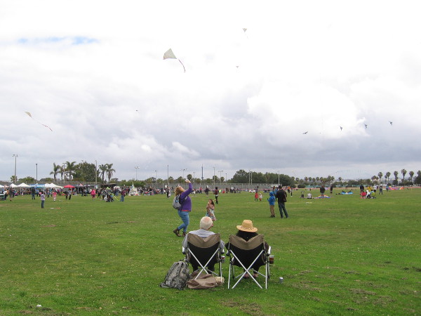 A couple has front row seats to a lot of colorful kite action at Robb Field in OB.