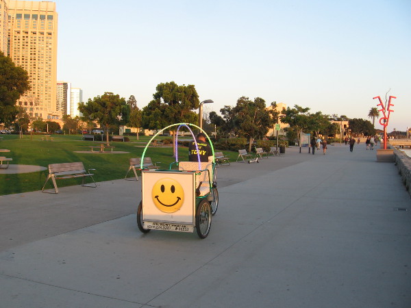 Smiley face on a pedicab heads toward four Urban Trees. The Port of San Diego public sculptures were recently moved from the Cruise Ship Terminal to Ruocco Park.