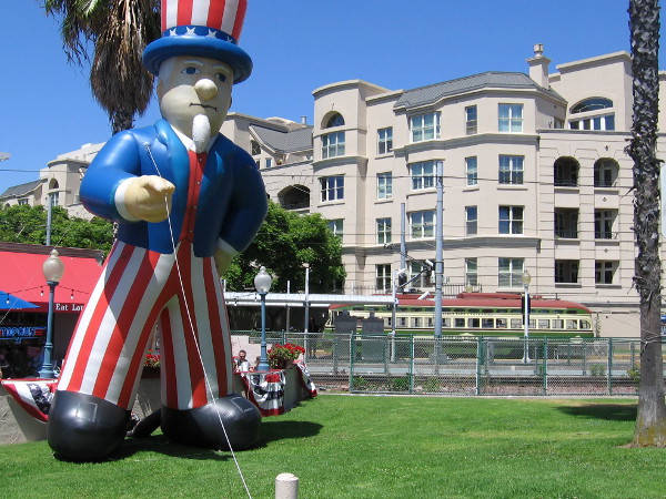 A restored PCC streetcar of the San Diego Trolley's Silver Line passes near Kansas City Barbeque. A huge inflatable Uncle Sam is out for the Memorial Day weekend.
