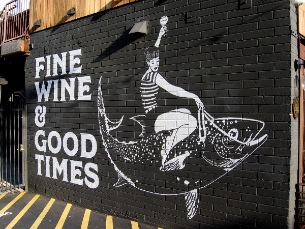 Riding a fish with wine glass raised high.