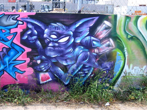 A wicked-looking character seems to be spray painting the graffiti next to him.