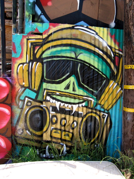 A character with sunglasses and headphones holds a boombox with his fang-like teeth.