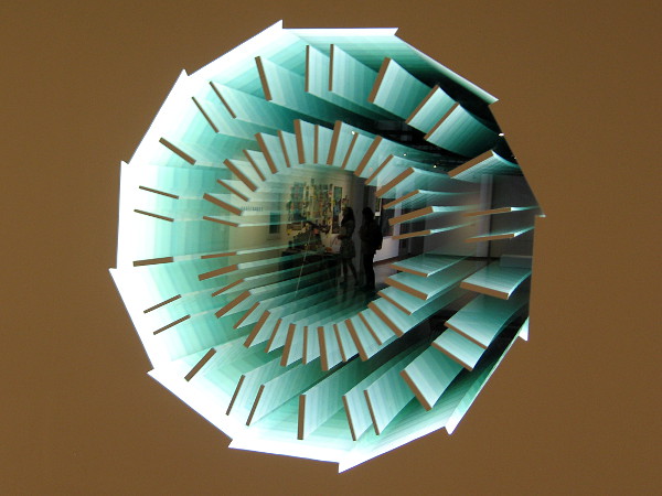 Art that creates an infinite reflection and contemplates the scale and structure of space and time. The two-way mirror is titled Down the Rabbit Hole (CMS Detector) by artist Adam Belt.